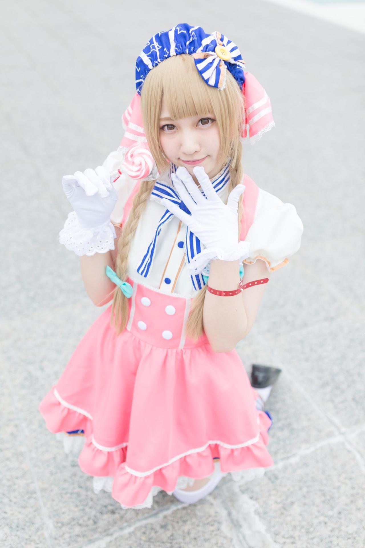 玖音さん扮南小鸟右手拿着棒棒糖，左手五指张开放在下巴前 跪姿 3/4侧面