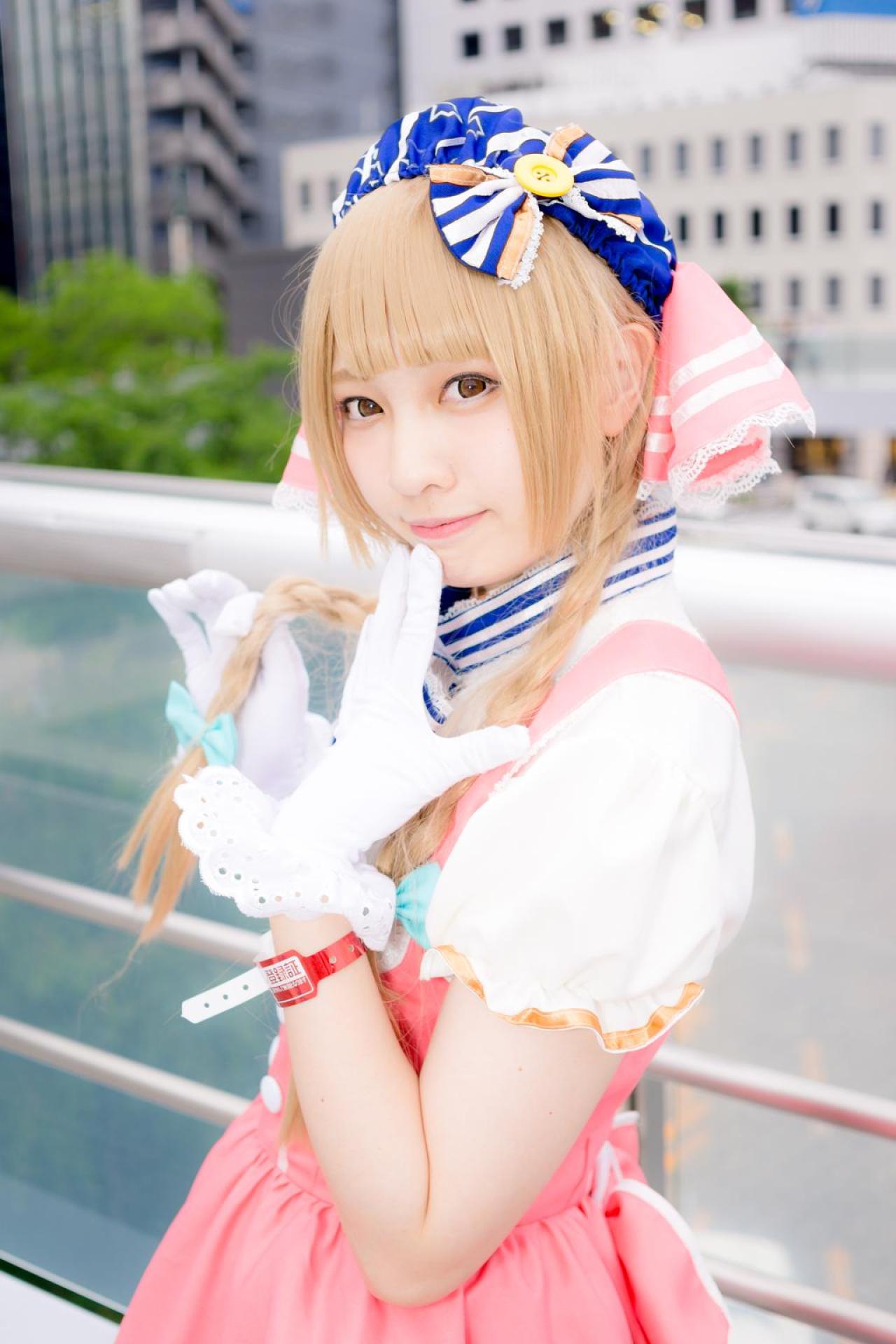 玖音さん扮南小鸟由右手捏着麻花辫，左手轻扶唇角 站在栏杆前