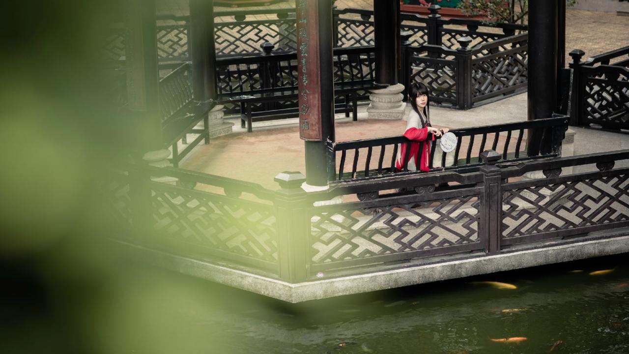 安姐姐坐在湖心亭的长椅上，持扇扶着椅背，侧身回眸