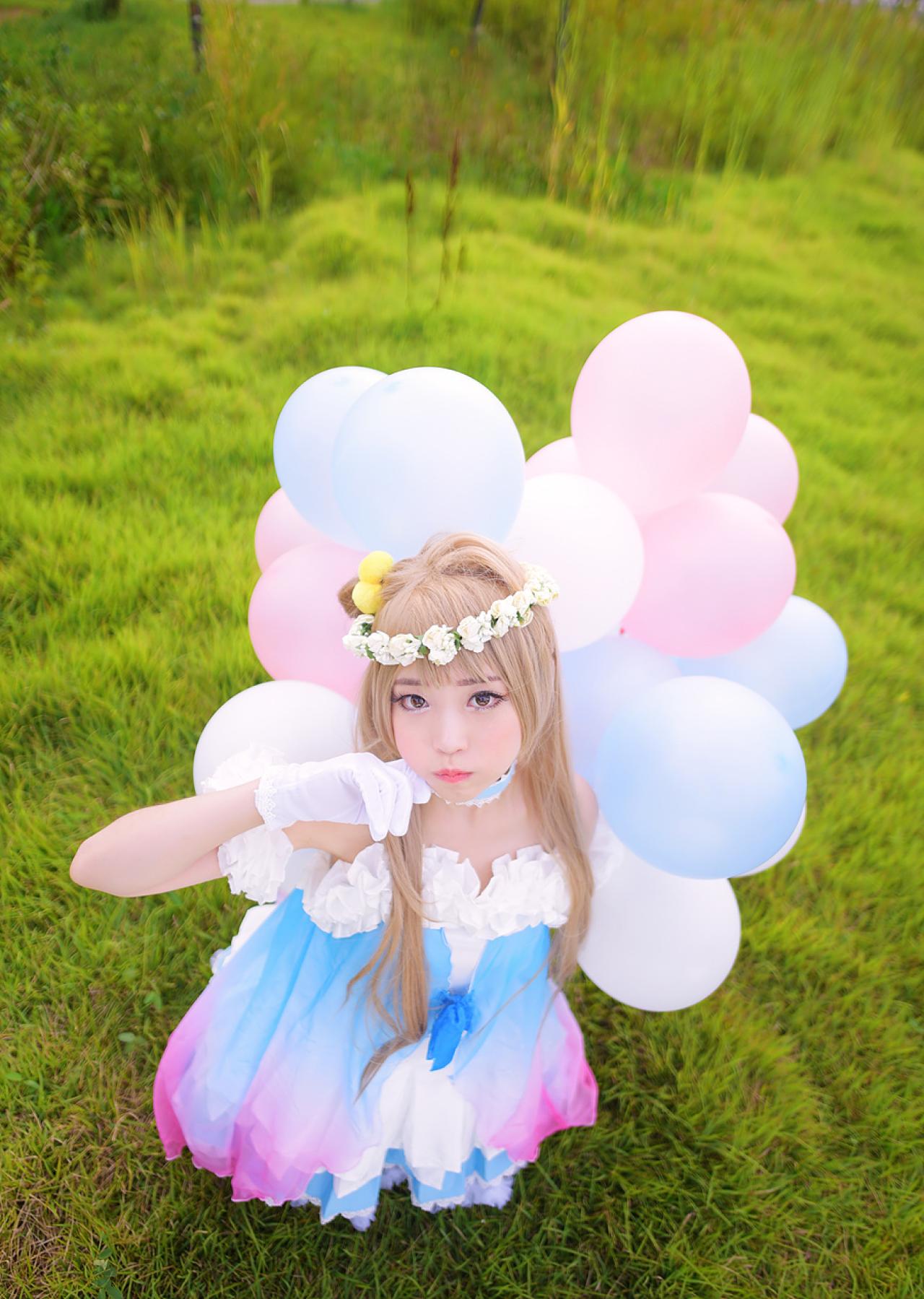 兔娘tomia扮南小鸟跪在草地上，左手拿着气球放在背后，右手轻抵脸庞，嘟嘴卖萌