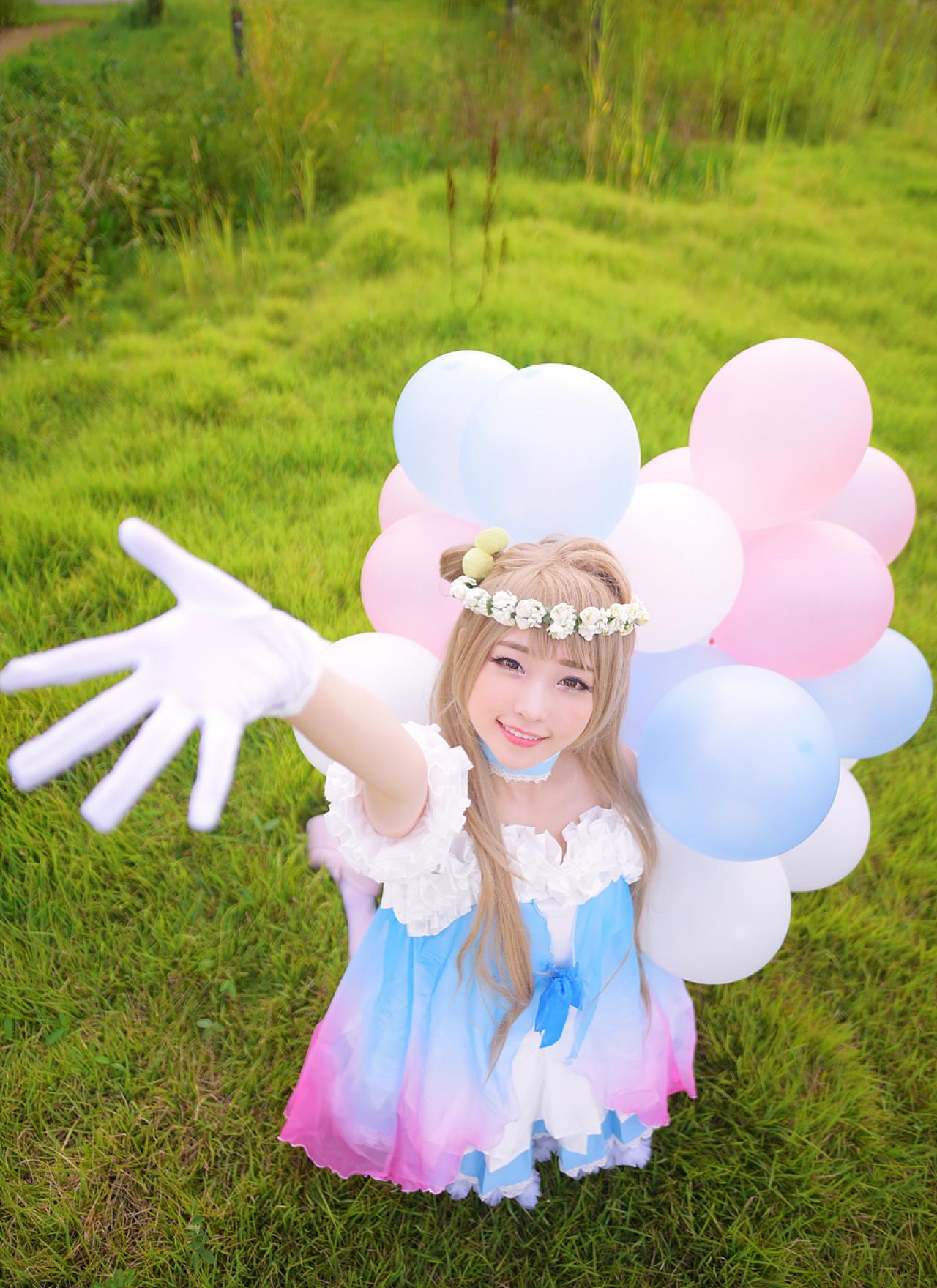 兔娘tomia扮南小鸟跪在草地上，左手拿着气球放在身后，抬起右臂，右手五指张开
