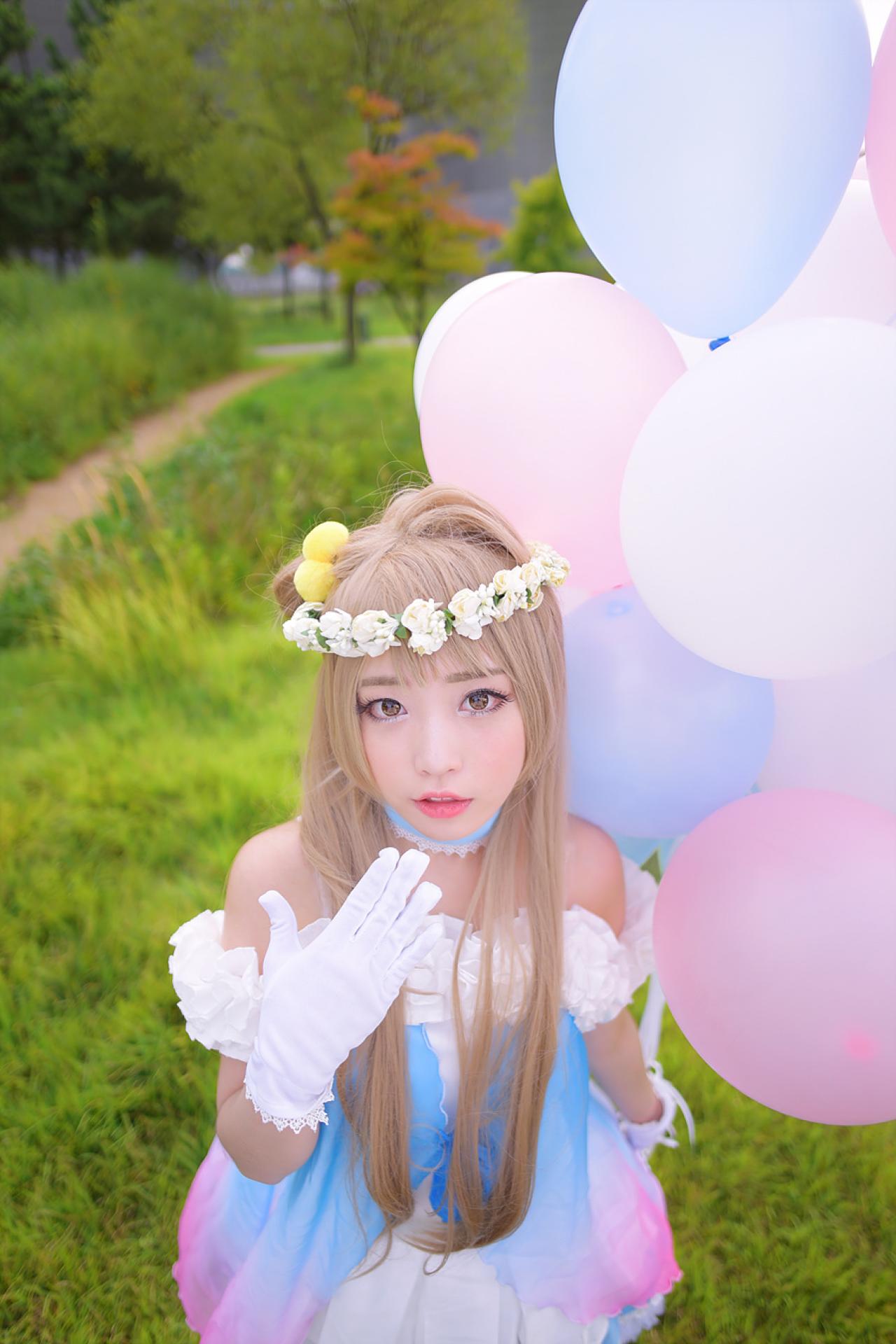 兔娘tomia扮南小鸟左手拿着气球放在身后，跪在草地上