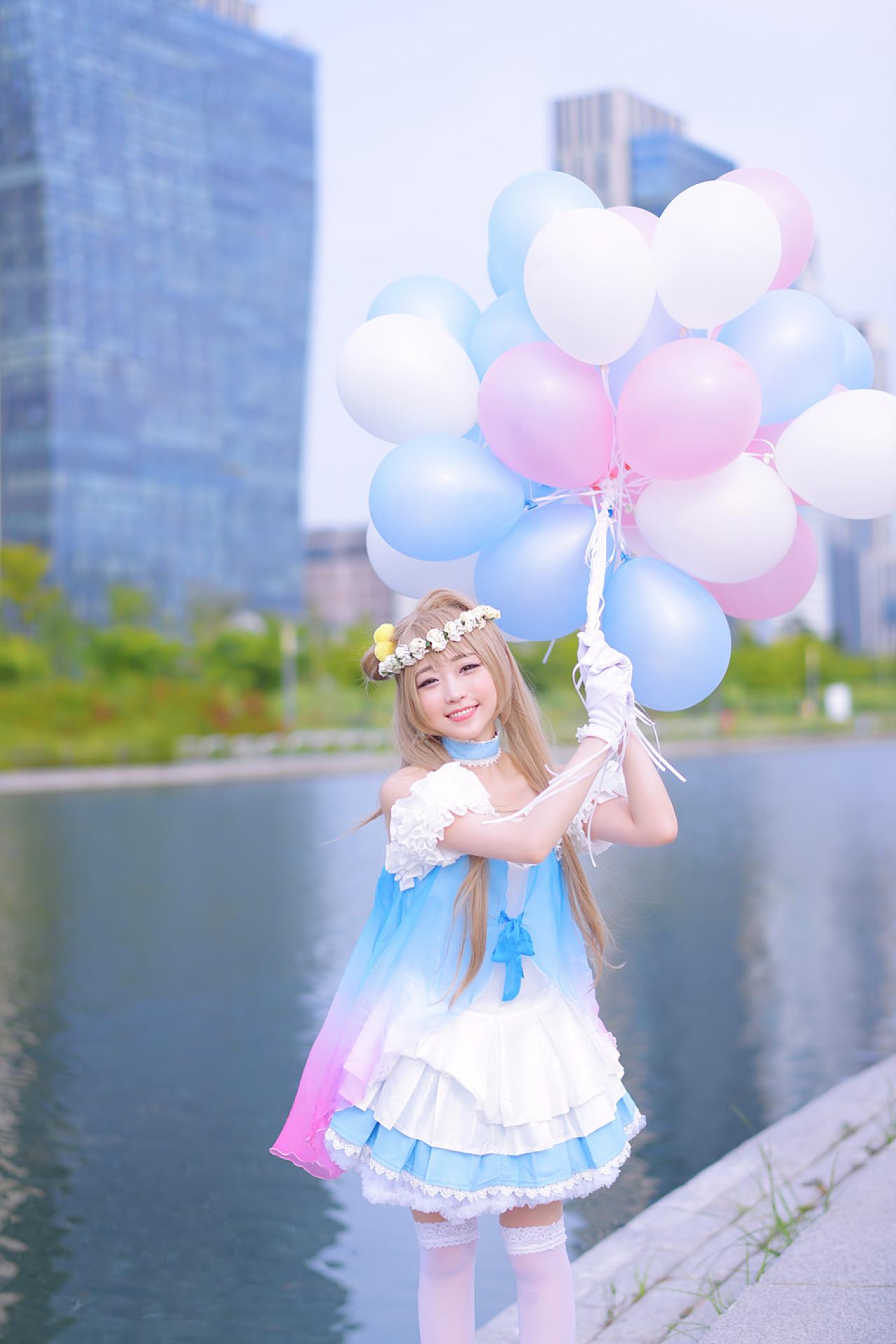 兔娘tomia扮南小鸟双手握着气球，站在河边
