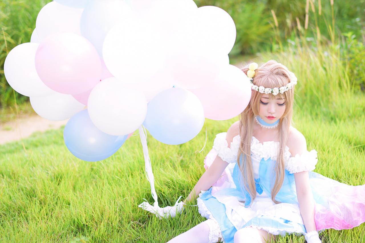 兔娘tomia扮南小鸟坐在草地上，右手拿着气球，看着草地