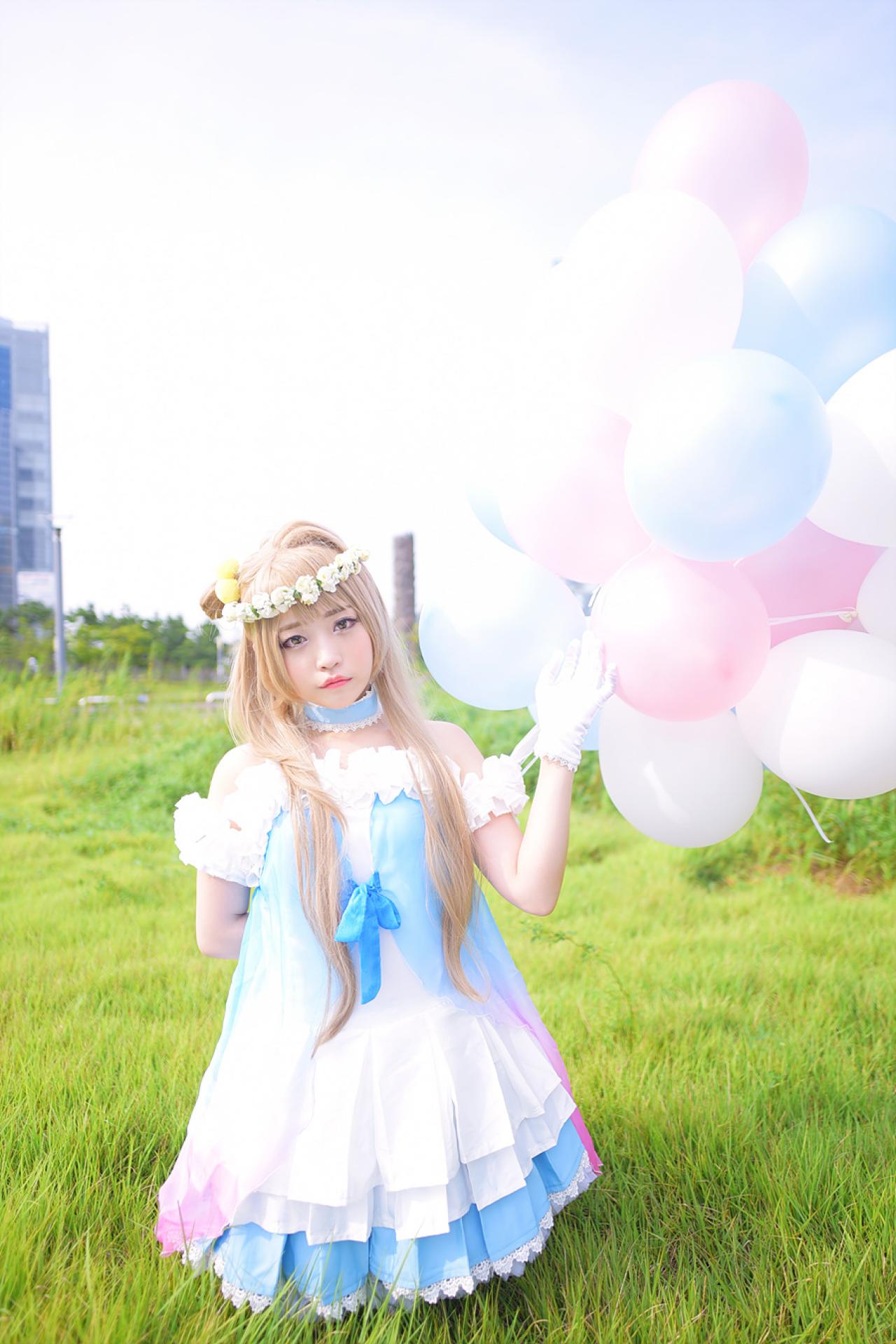 兔娘tomia扮南小鸟左手拿着气球放在身后，抬起右臂，跪在草地上