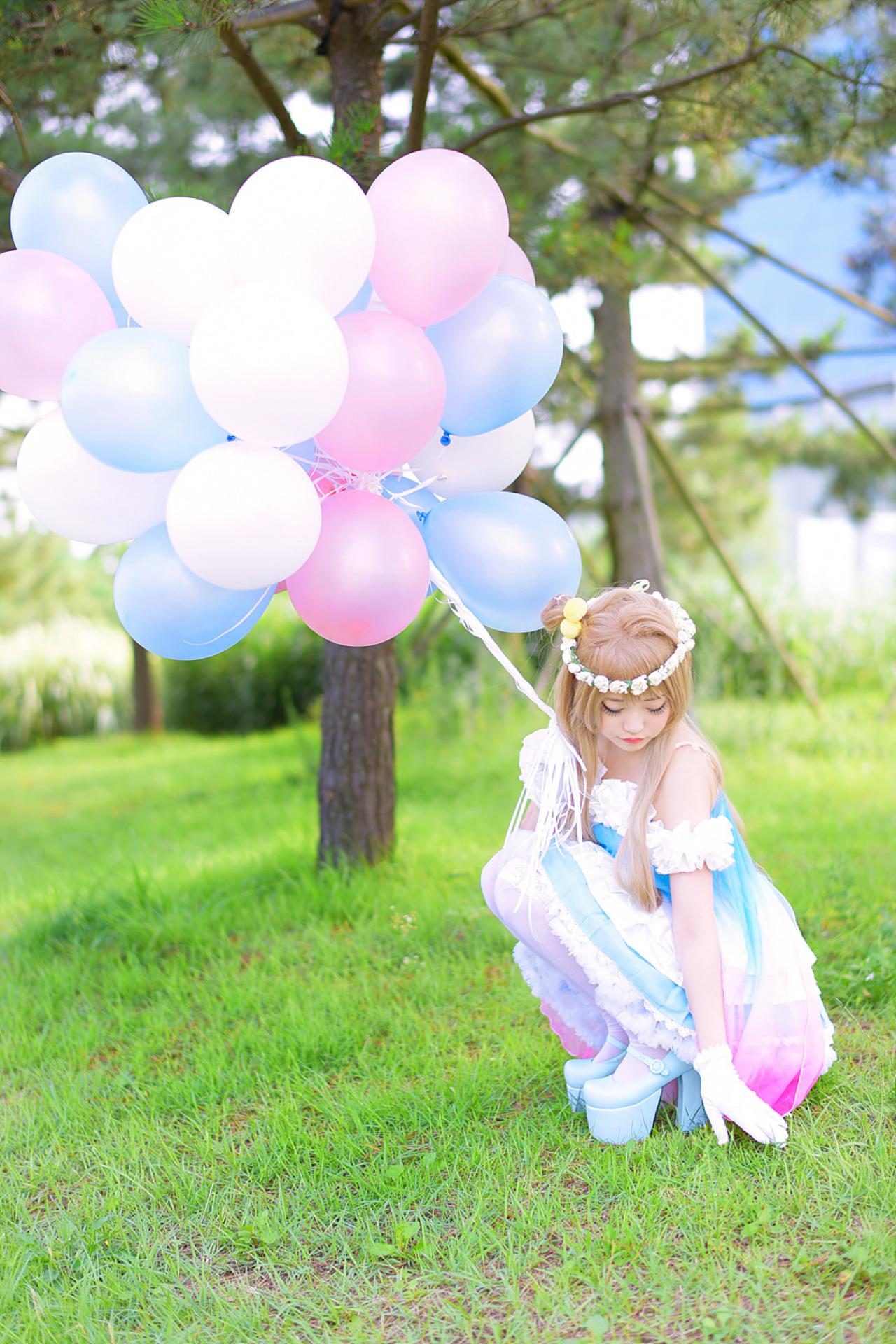 兔娘tomia扮南小鸟右手握着气球，侧身蹲在草地上，左手在草地上画圈圈