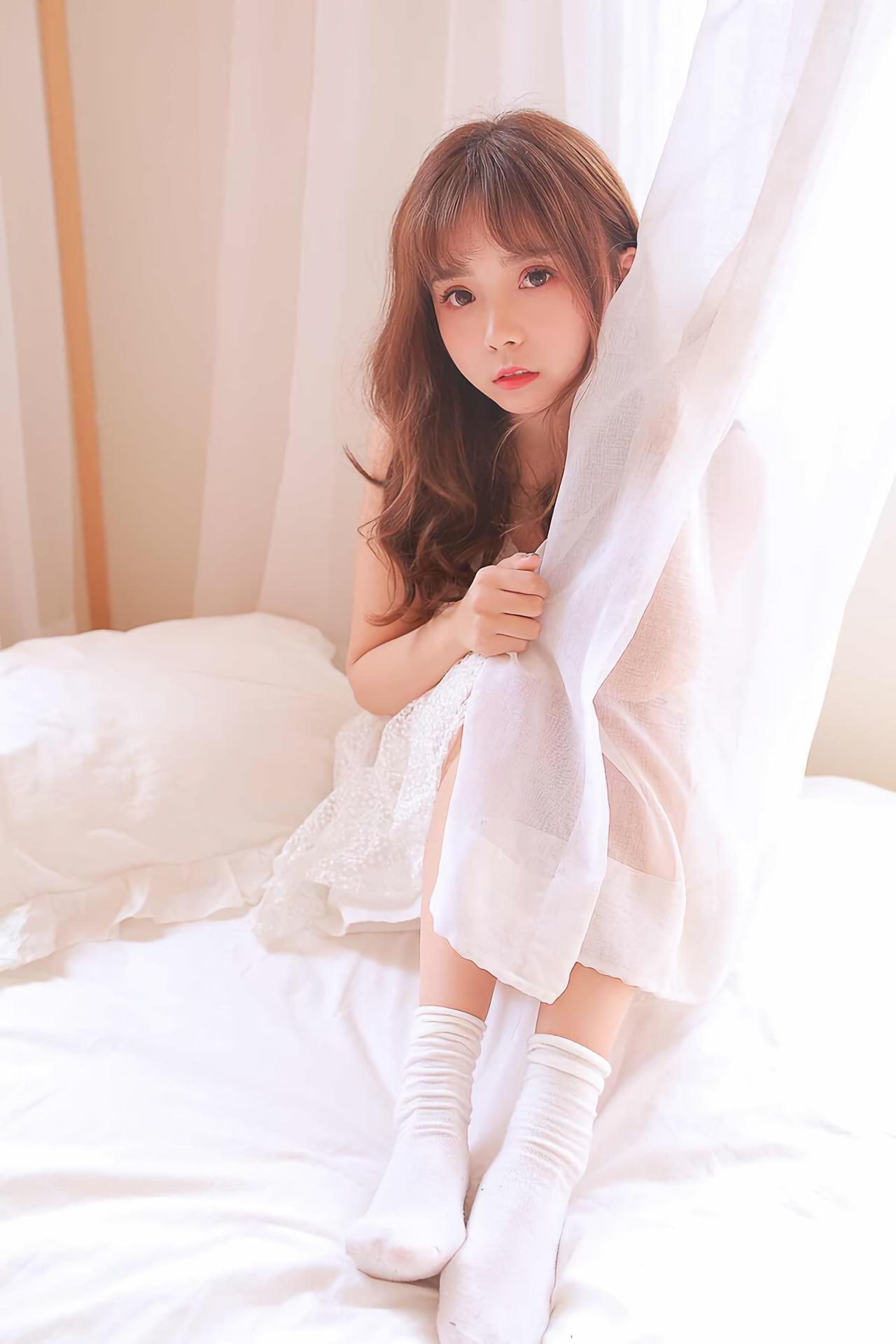 水蜜桃味的甜坐在床上，躲在白色窗帘后