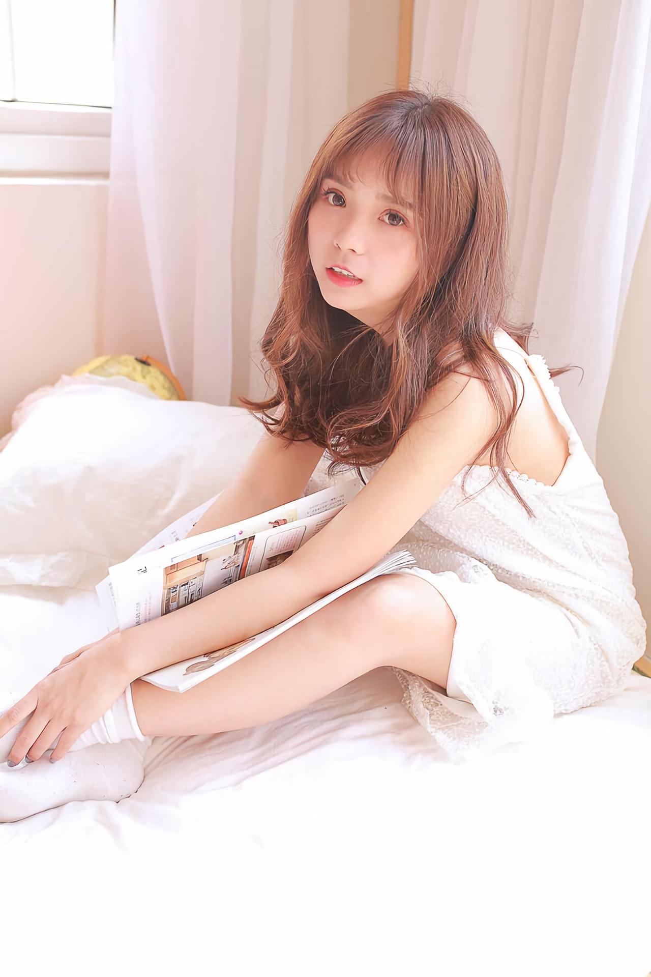 水蜜桃味的甜坐在床上，书本枕在腿上