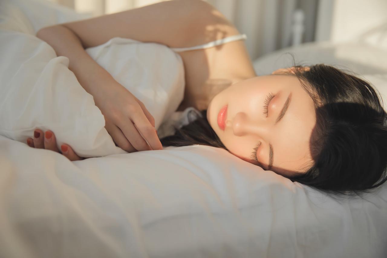 少女怀抱着被子，侧身躺在床上