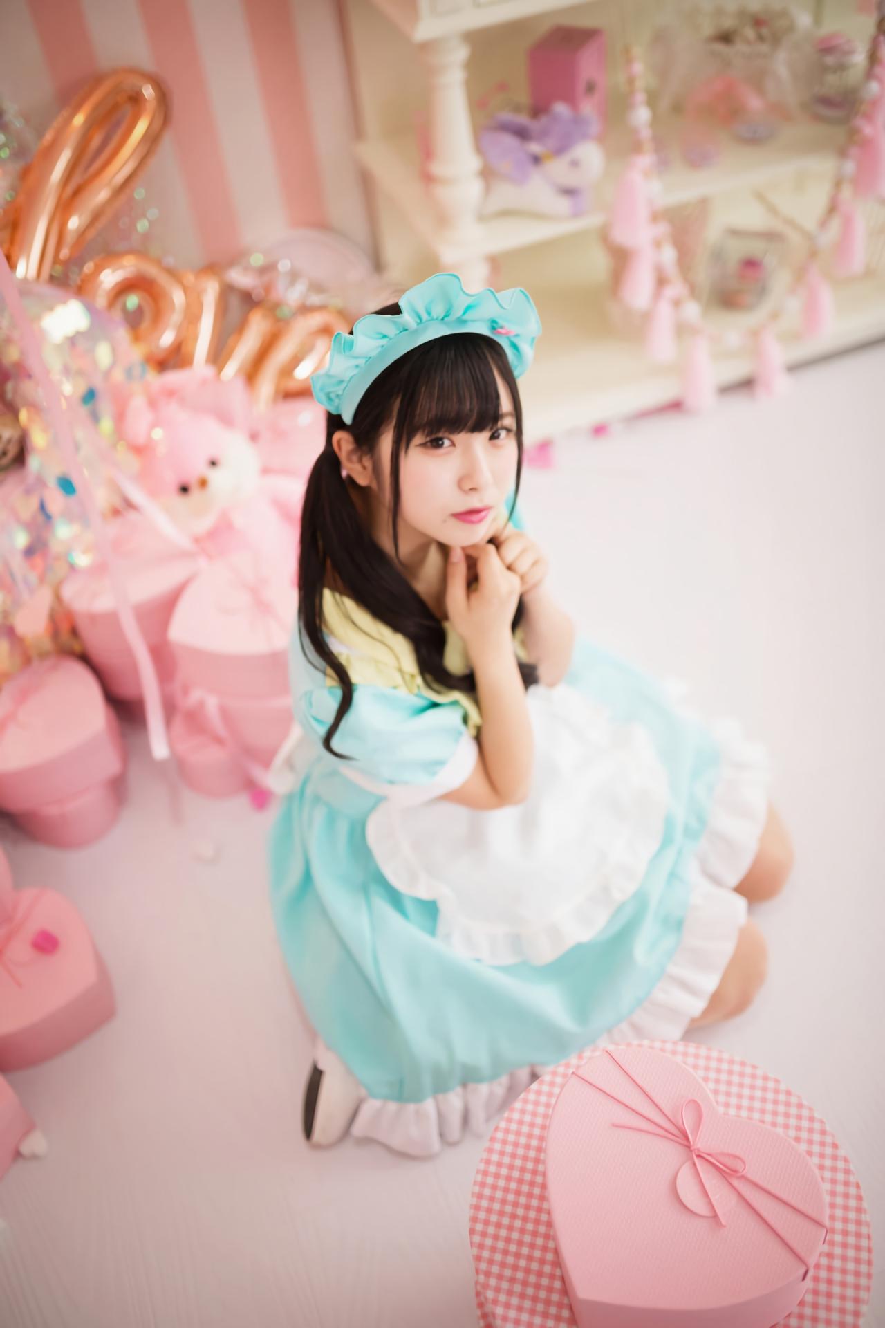 谷口彩菜跪坐在地上，双手叠放在胸前，旁边放着粉色桃心礼盒 3/4侧面