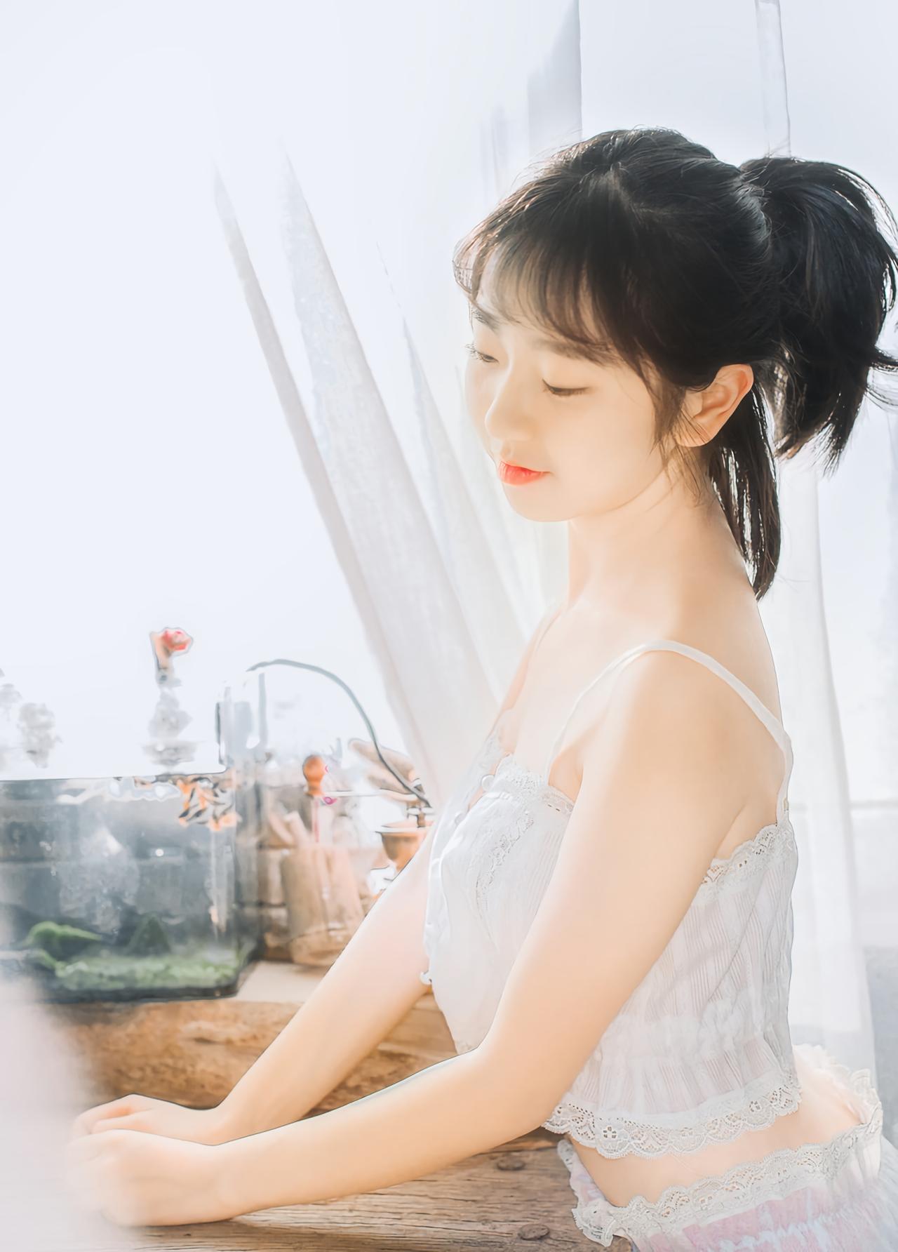 萌妹子侧身站在桌子旁，双手扒在桌子上