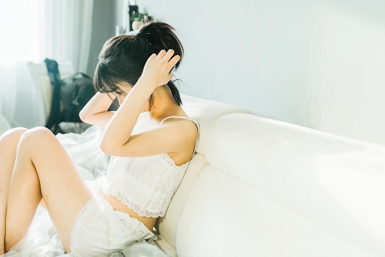 萌妹子侧身靠在沙发上，双手拢起头发