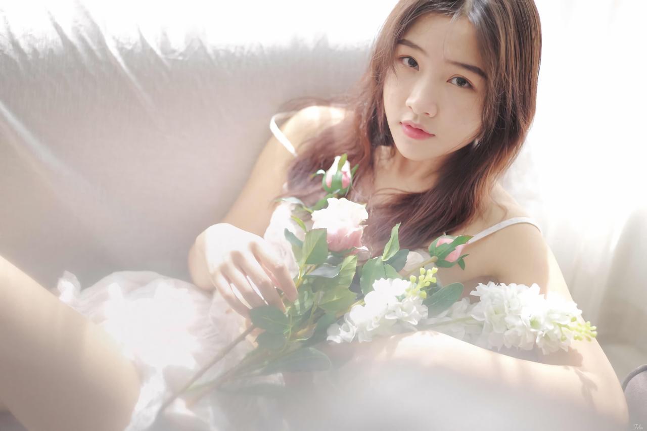 萌妹子侧身靠在沙发上 双手捧着手捧花 白色窗帘盖在沙发上