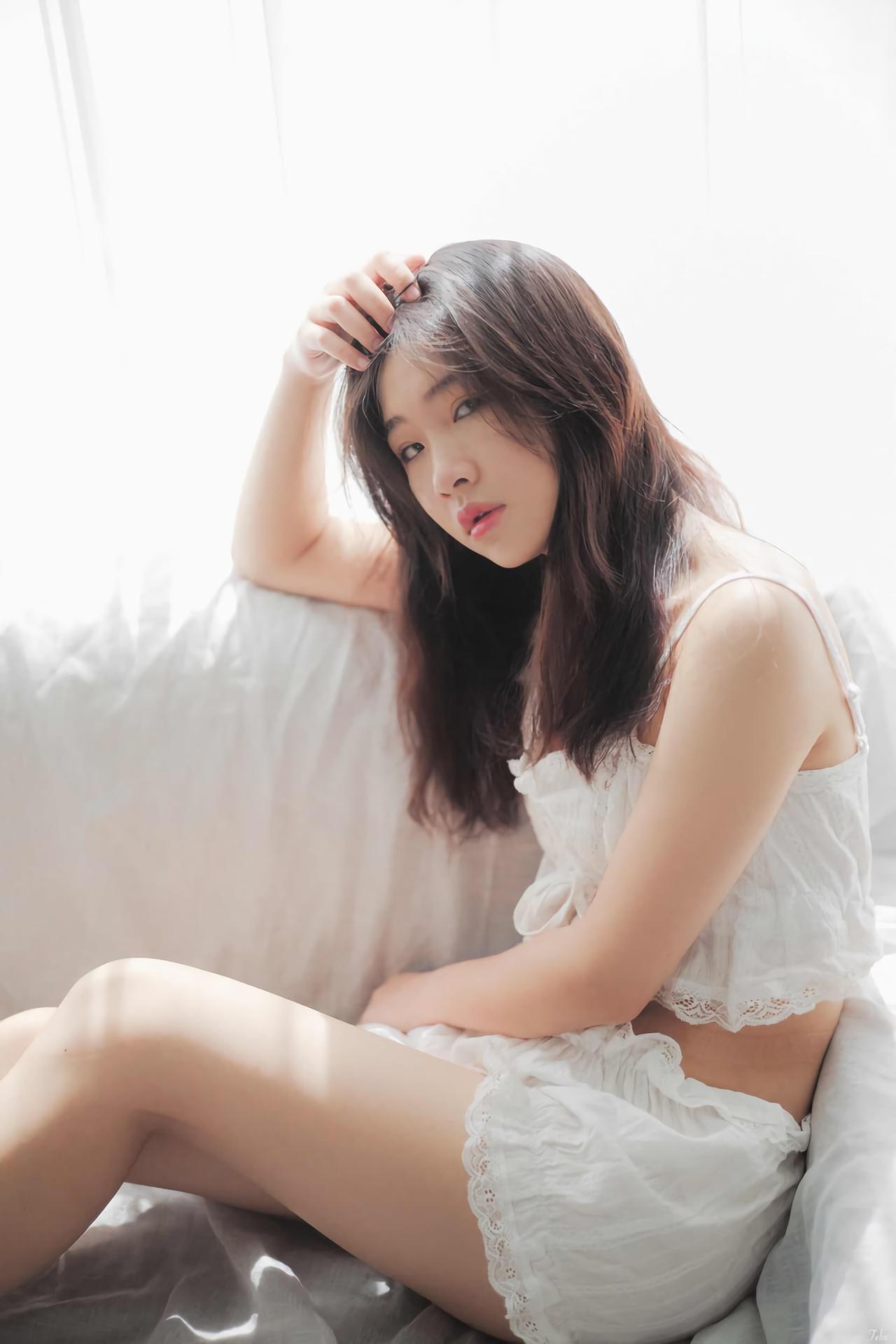 萌妹子侧身靠在沙发上 轻抚刘海儿 白色窗帘盖在沙发上