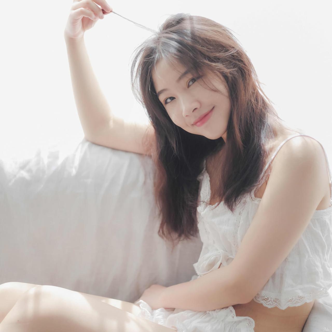 萌妹子侧身靠在沙发上 拉起发丝 微笑 白色窗帘盖在沙发上