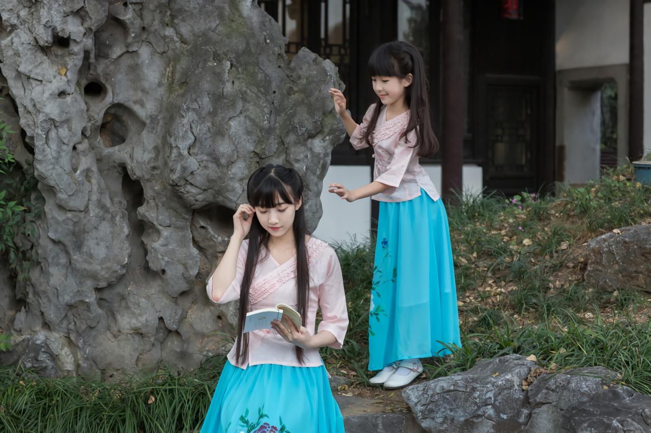 大乔坐在假山前看数 小乔扶着假山站在身后