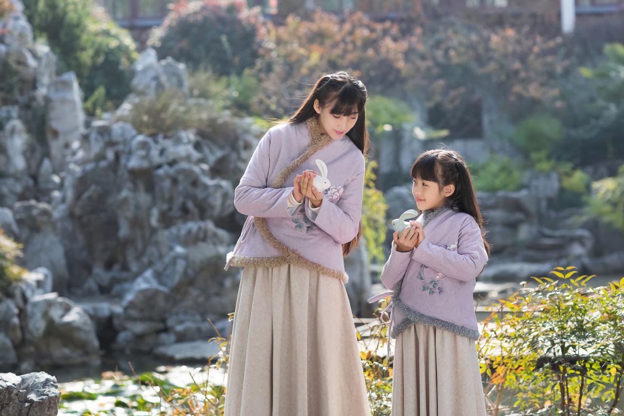 大乔和小乔坐在石头上双手捧着小兔子 站在池塘旁