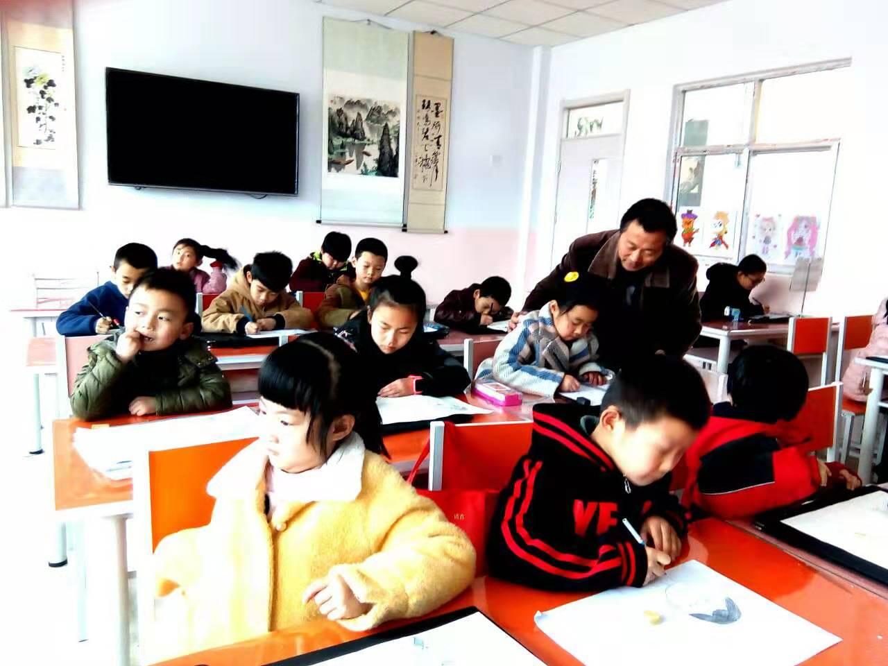 老师正在给一部初小班的学生辅导人物画作业