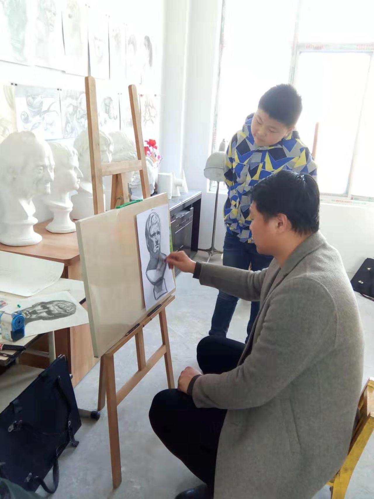 老师正在给圆梦画室素描二班的学生辅导素描作业