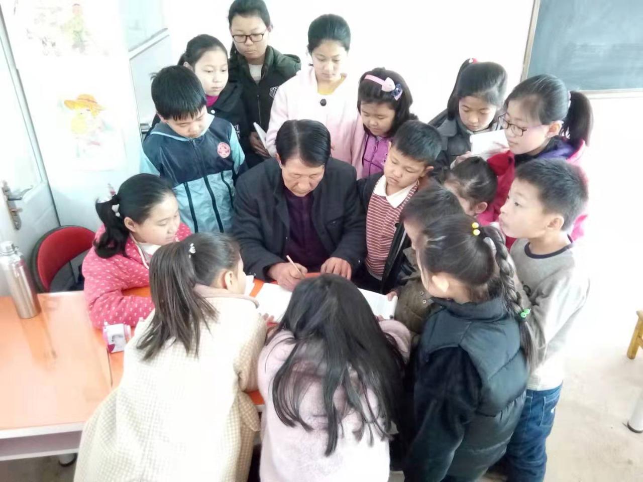 圆梦画室硬笔书法二班的学生正围在老师身旁，听老师讲解