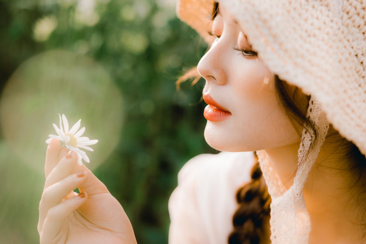 双马尾麻花辫穿着白色连衣裙花戴着草帽少女右手手指捏着雏菊侧脸的脸部特写 侧脸照