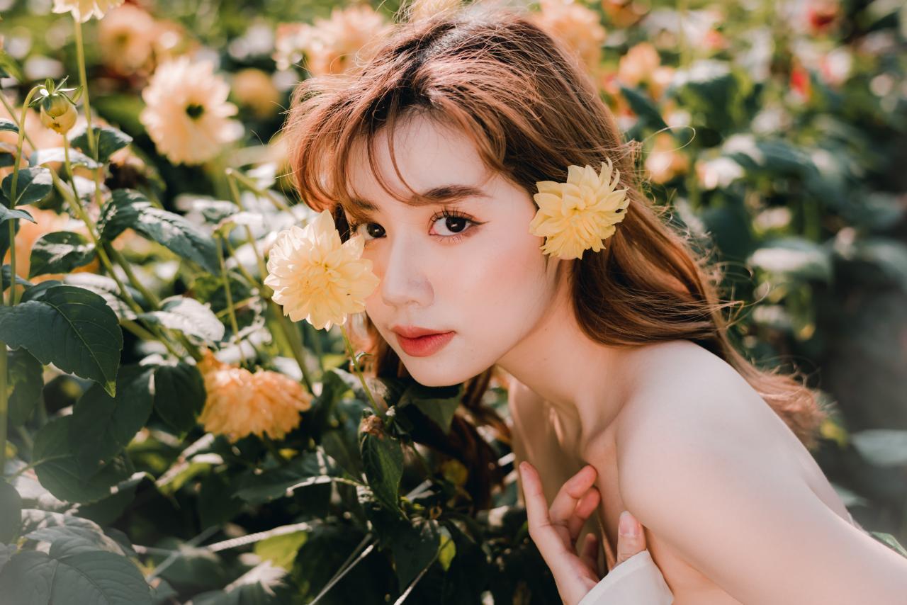 脸轻轻贴在菊花上 头戴大丽花菊花 绿色抹胸连衣裙 白色小菊花披肩 棕色长发少女 侧面照 脸部特写