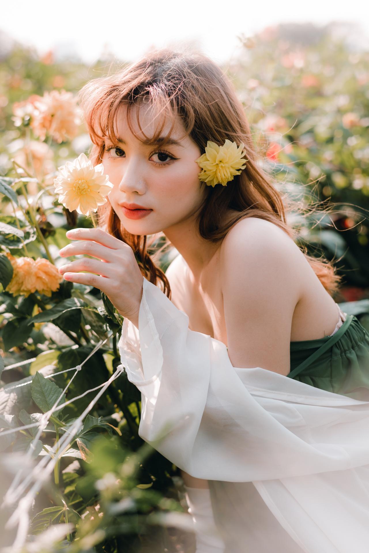 手持大丽花菊花 头戴菊花 绿色抹胸连衣裙 白色小菊花披肩 棕色长发少女 侧面照 蹲姿