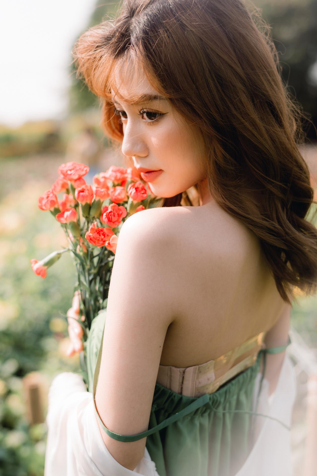 手捧红色小菊花 绿色抹胸连衣裙 白色小菊花披肩 棕色长发少女 回眸照 半身照 站姿