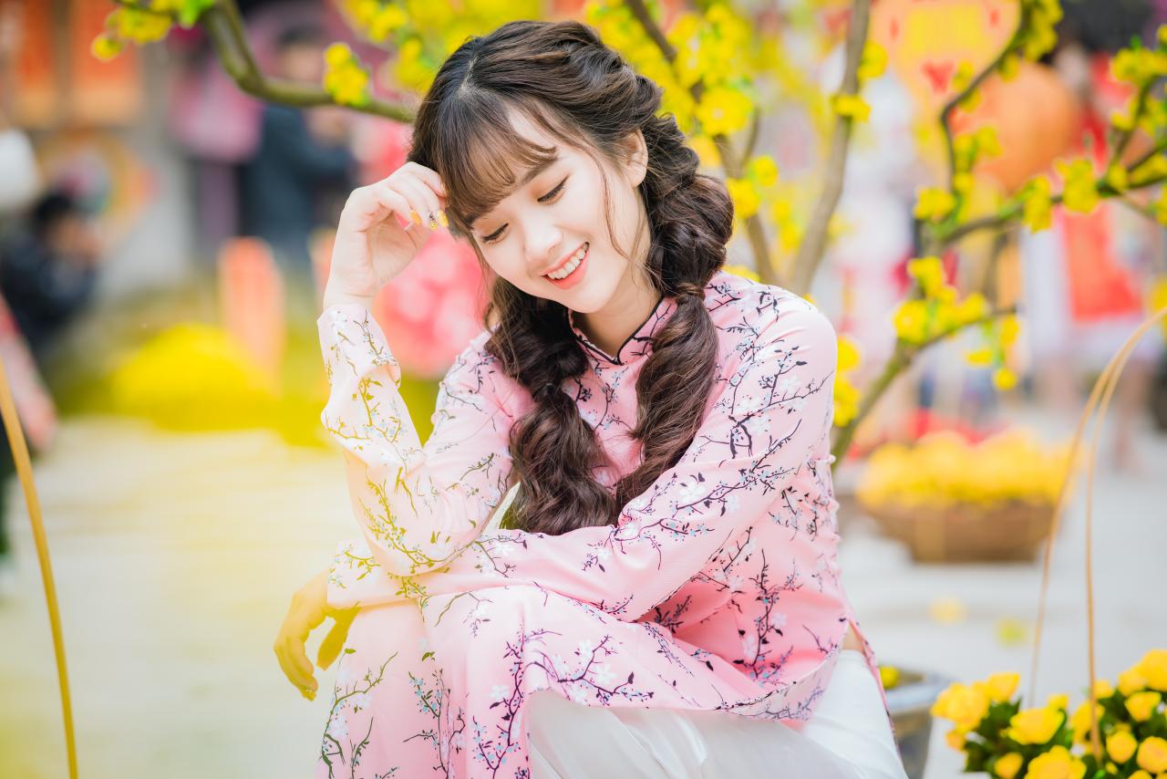 棕色双马尾卷发，齐刘海儿，穿着粉色旗袍白色长裤的少女 蹲姿 上半身照 4/3侧面照 横幅 咧嘴露齿微笑 闭眼低头 垂首 思考姿势 腊梅 黄梅 花篮 橙色灯笼